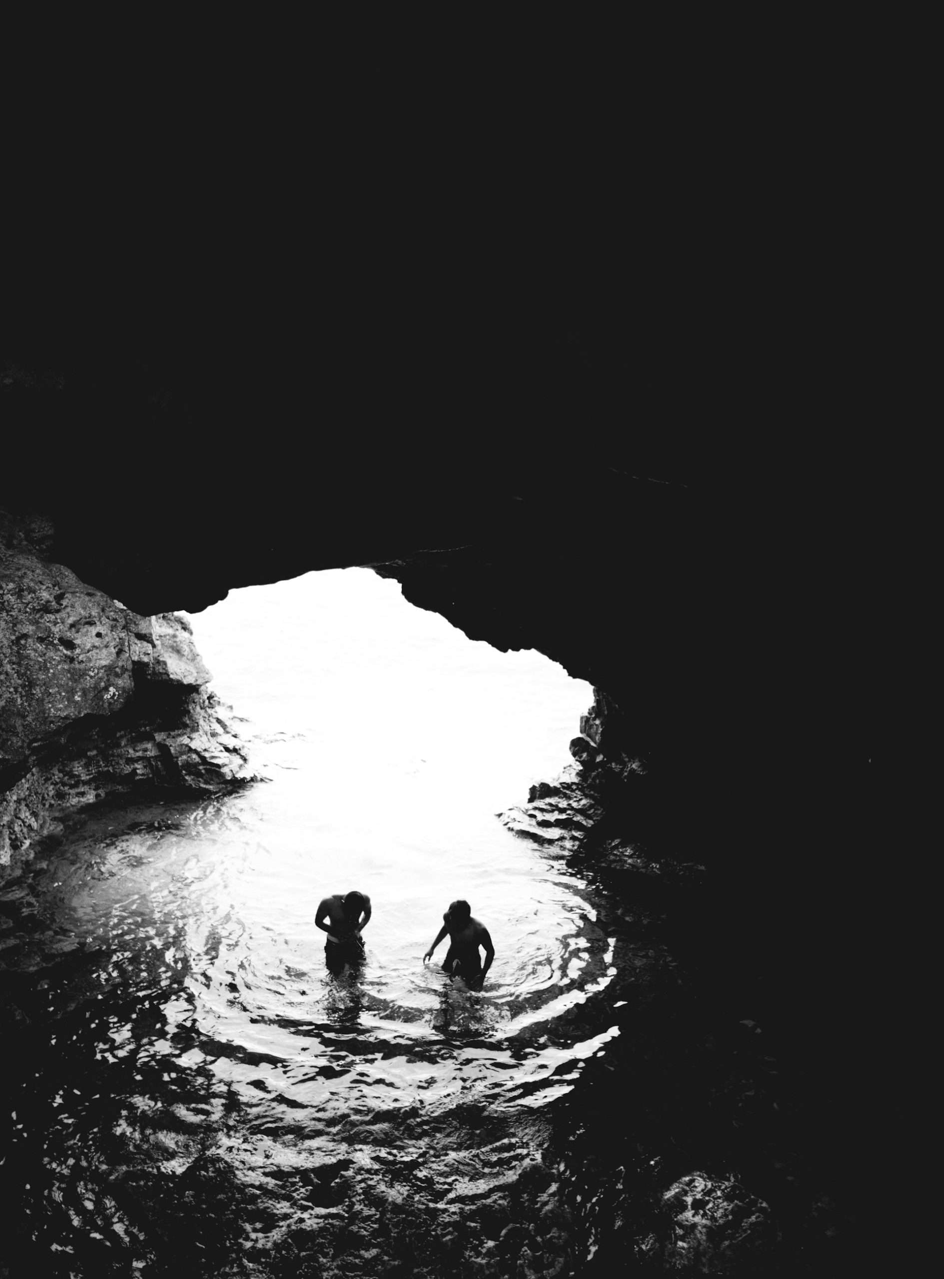 two men in cave with body of water