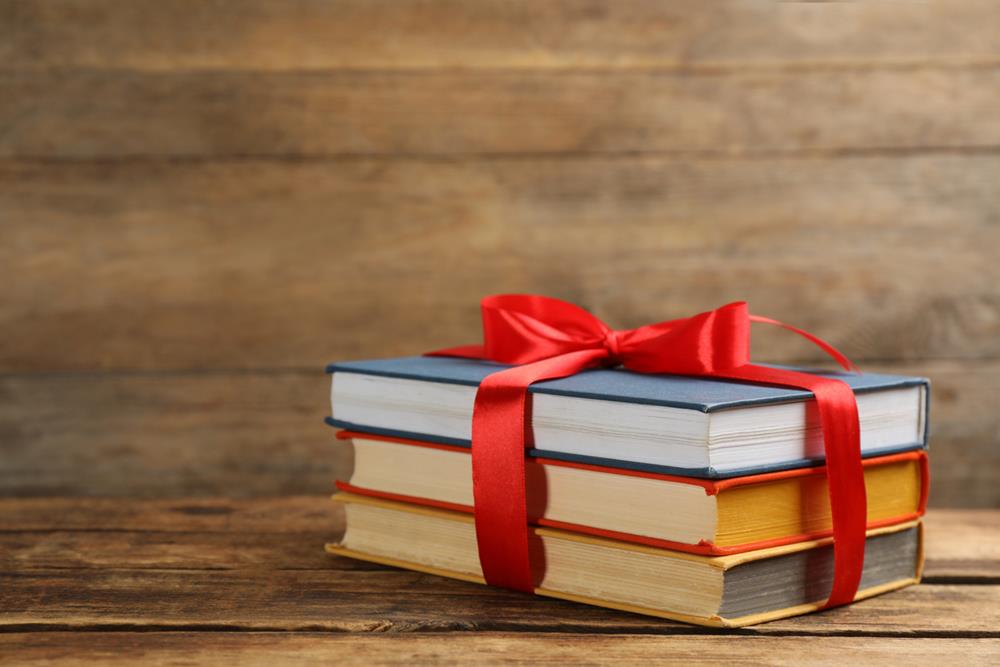 Different books tied with red ribbon on wooden table