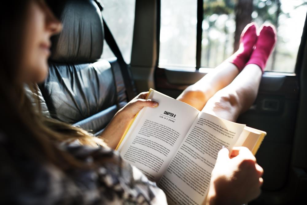 A girl reading a book inside a car